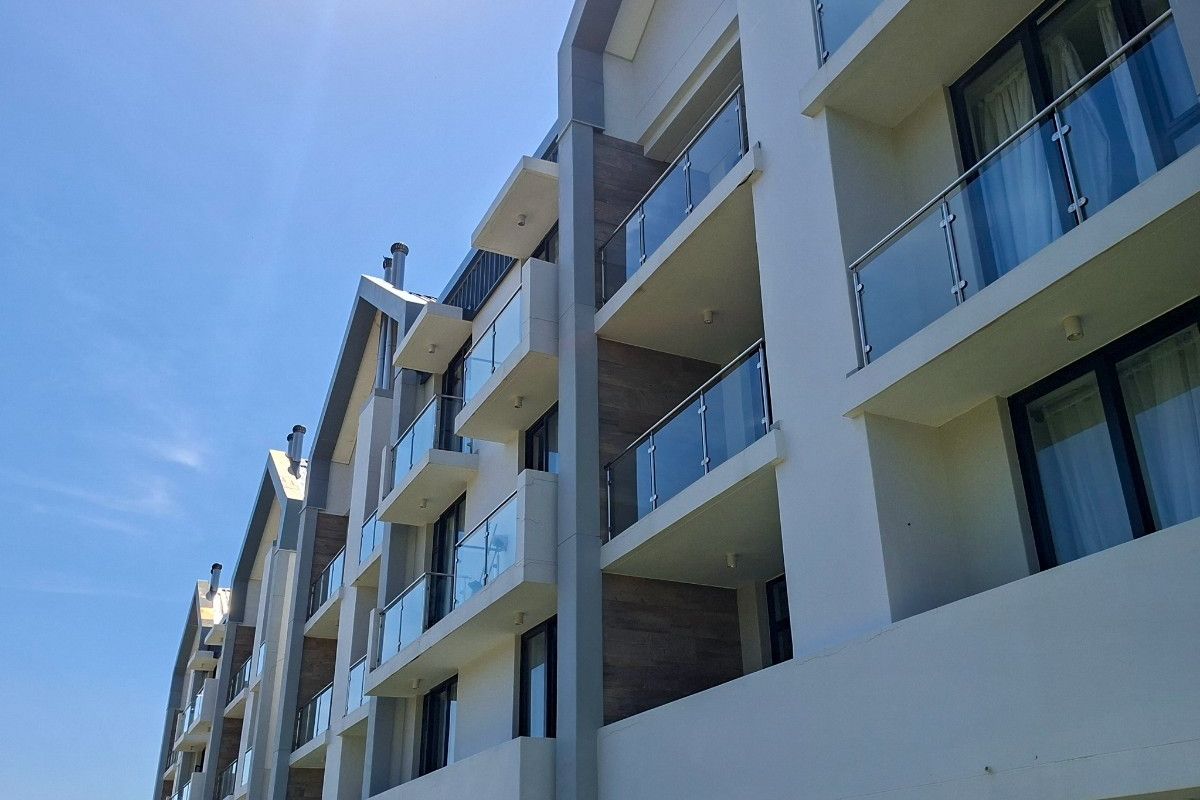 Modern apartment building exterior featuring multiple levels with private balconies, glass balustrades, and contemporary architectural finishes.