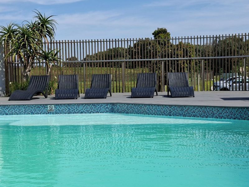 A well-maintained swimming pool area featuring mosaic tile detailing, composite decking, and secure metal perimeter fencing.