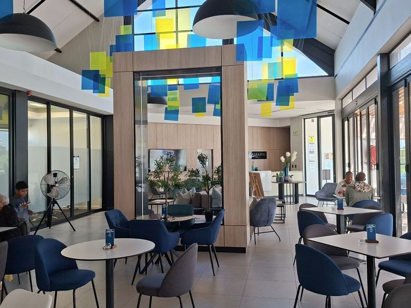 A modern, high-ceilinged clubhouse featuring large format floor tiles, expansive glass partitions, and contemporary architectural design, suitable for communal gatherings and events.