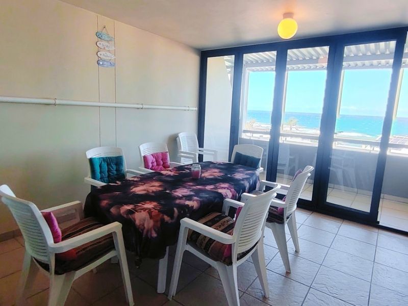 A covered balcony featuring tiled flooring and large sliding glass doors that provide access to an outdoor area with ocean views.