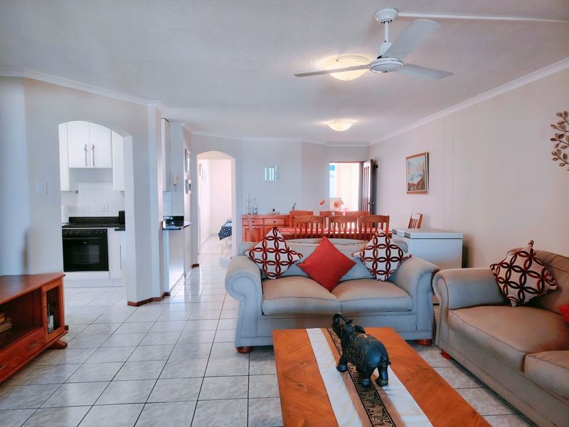 Spacious open-plan living and dining area featuring tiled floors, a ceiling fan, and an adjoining kitchen with built-in cabinetry and appliances.