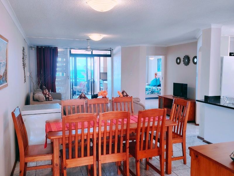 Open plan living and dining area featuring tiled flooring, neutral walls, and direct access to a balcony through sliding glass doors.