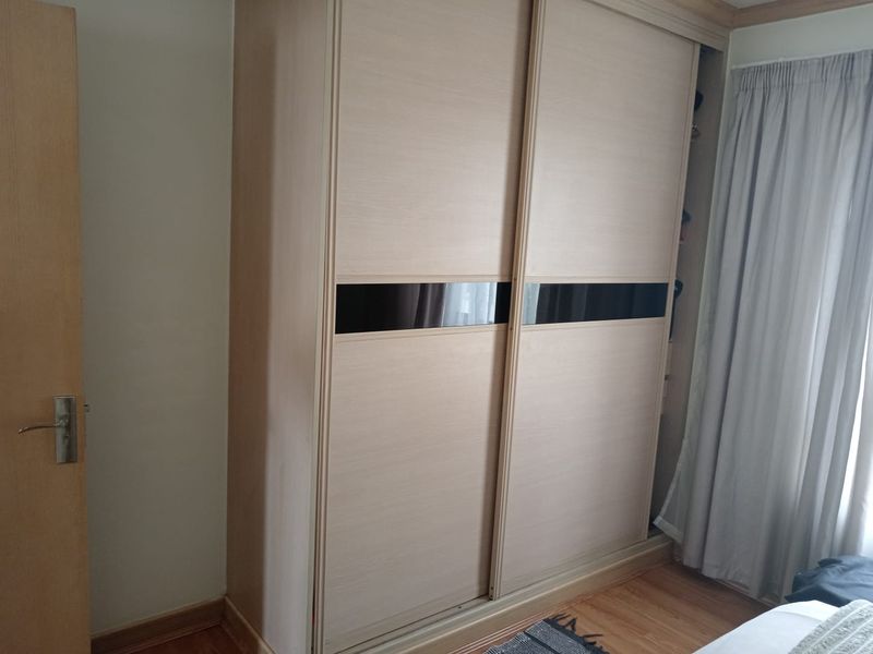 A bedroom featuring a modern built-in sliding door wardrobe with wood-grain finish and laminate flooring.
