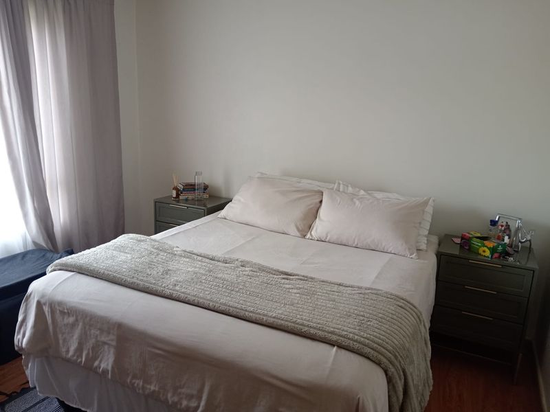A comfortable bedroom featuring laminate flooring and neutral wall finishes, providing a clean and functional space.
