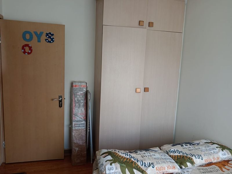 A bedroom featuring a light wood-toned built-in wardrobe and laminate flooring, providing functional storage space.