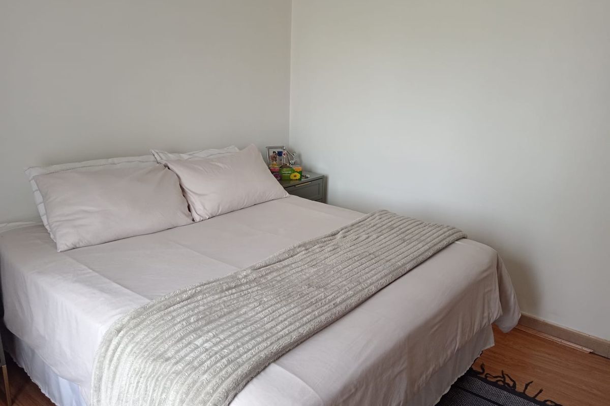 A simple bedroom featuring laminate flooring and neutral wall finishes, providing a clean and functional space.