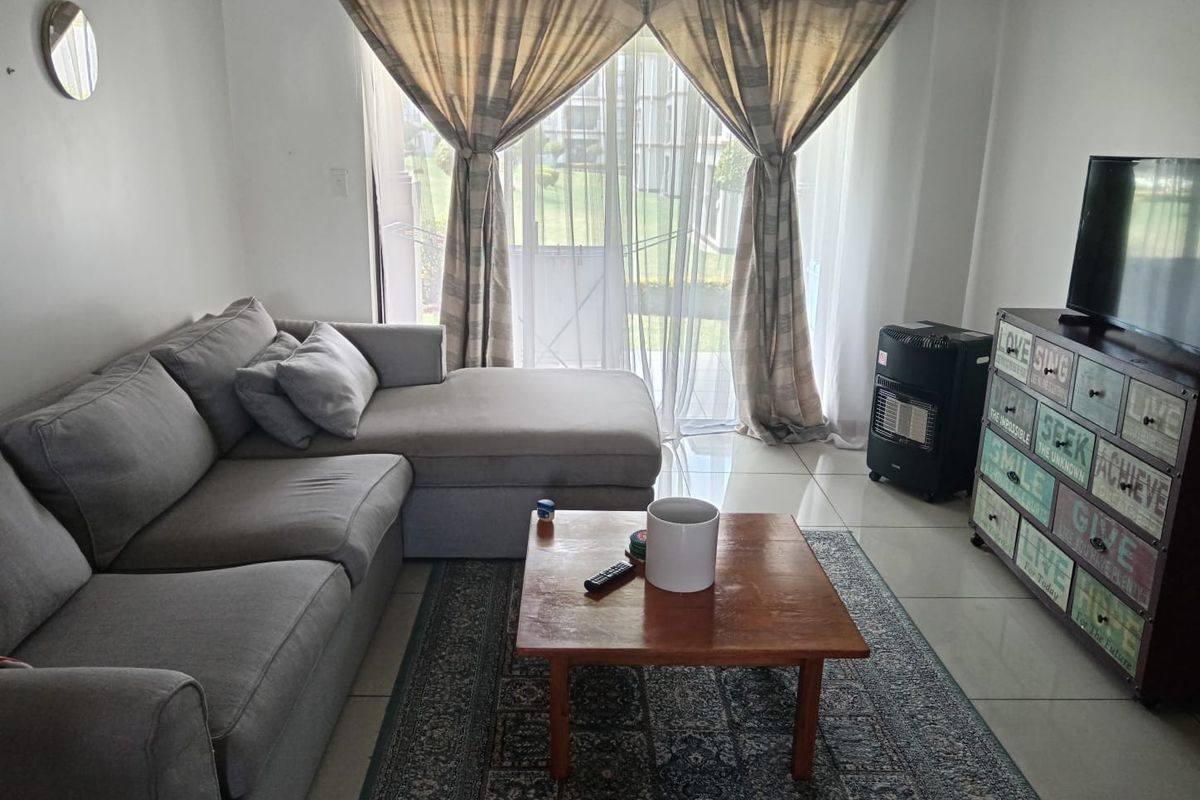 A comfortable living room featuring tiled flooring and a large sliding glass door that provides natural light and access to the outdoor area.