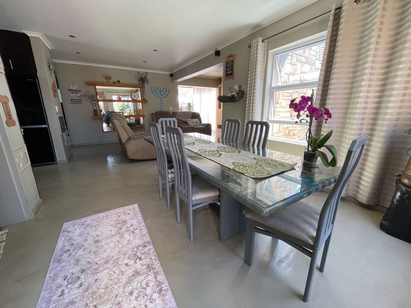 Spacious open-plan living and dining area featuring polished concrete floors, recessed lighting, and large windows allowing for ample natural light.