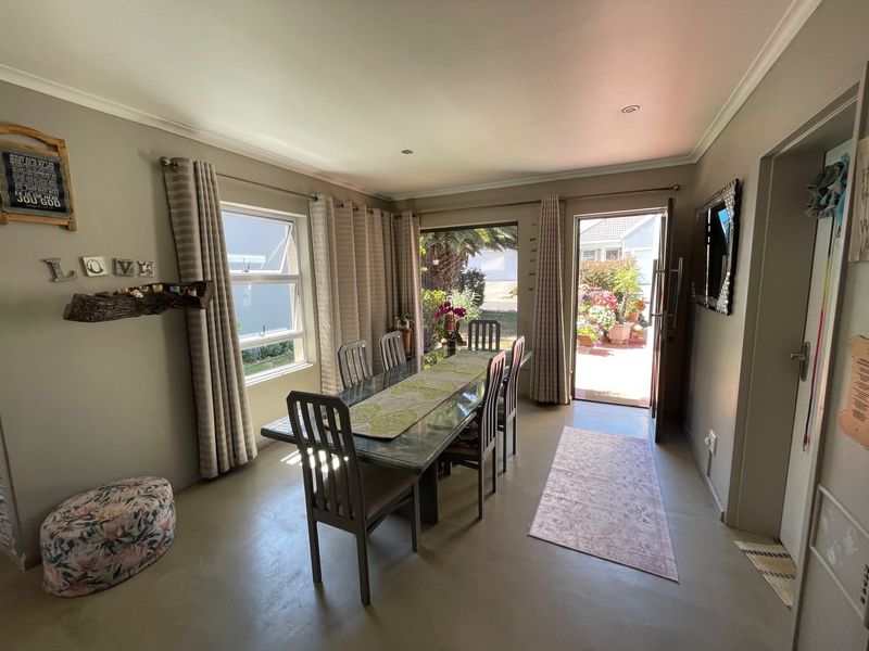 A bright dining room featuring polished concrete floors, recessed lighting, and direct access to an outdoor patio area through a sliding door.