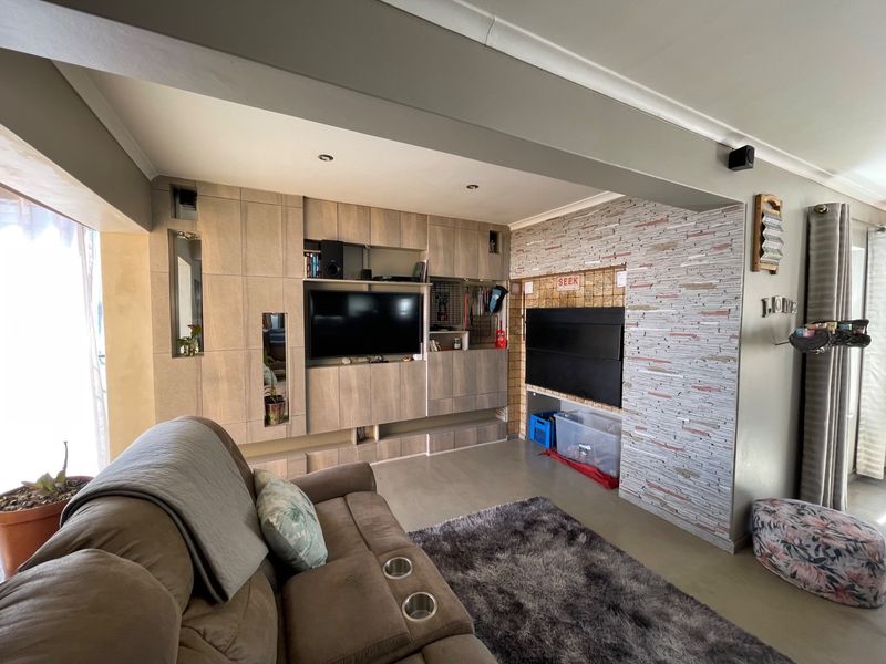 Living room featuring a custom built-in media unit and a decorative stone veneer feature wall with recessed lighting.