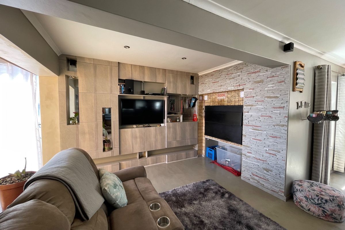 Living room featuring a custom built-in media unit and a decorative stone veneer feature wall with recessed lighting.