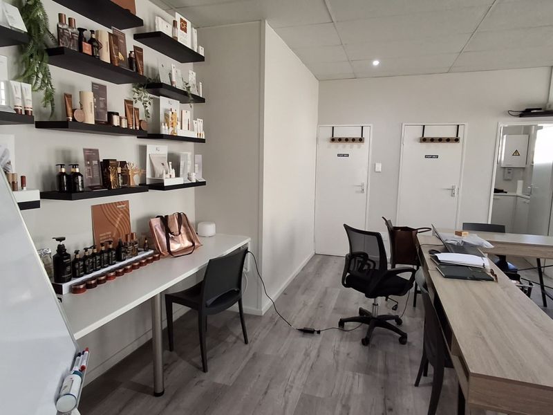 A well-maintained office space featuring laminate flooring, suspended ceiling with recessed lighting, and built-in shelving units, suitable for professional use.