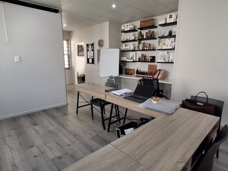 A functional office space featuring modern laminate flooring, recessed ceiling lighting, and integrated wall shelving for organized storage.