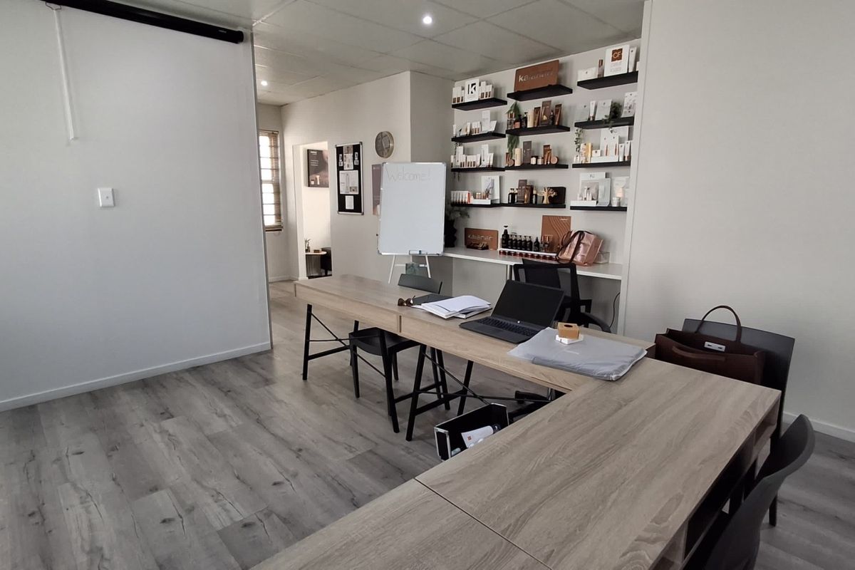 A functional office space featuring modern laminate flooring, recessed ceiling lighting, and integrated wall shelving for organized storage.