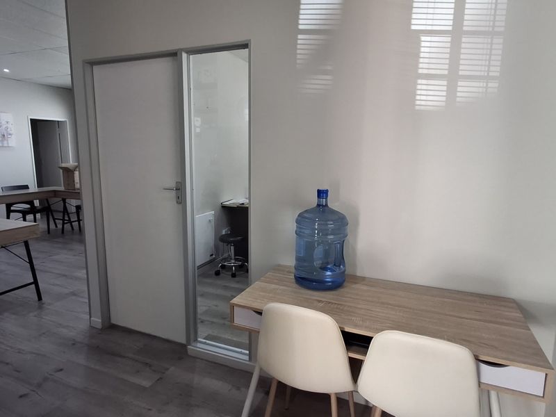 A functional office space featuring modern laminate flooring, a glass-paneled door, and a clean, neutral interior design suitable for professional use.