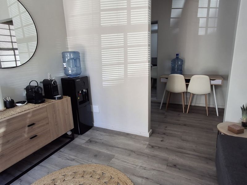 A modern office space featuring light wood-tone laminate flooring and a clean, neutral interior layout with a partitioned work area.