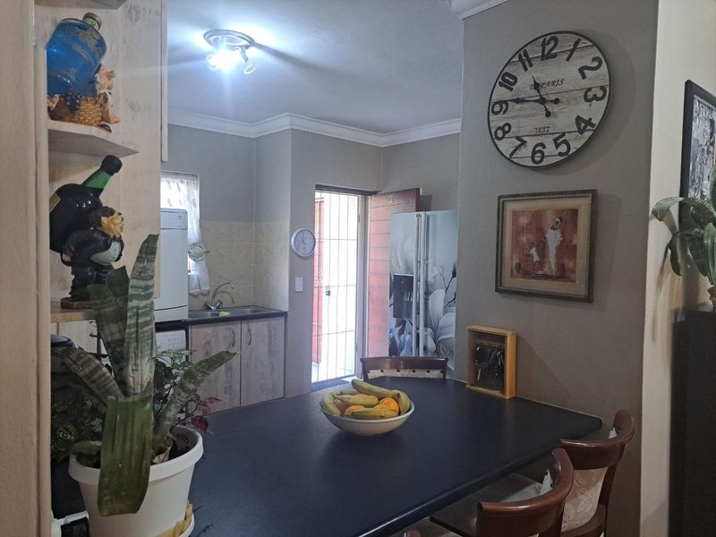 Open plan kitchen and dining area featuring built-in cabinetry, tiled backsplash, and direct access to an exterior security gate.