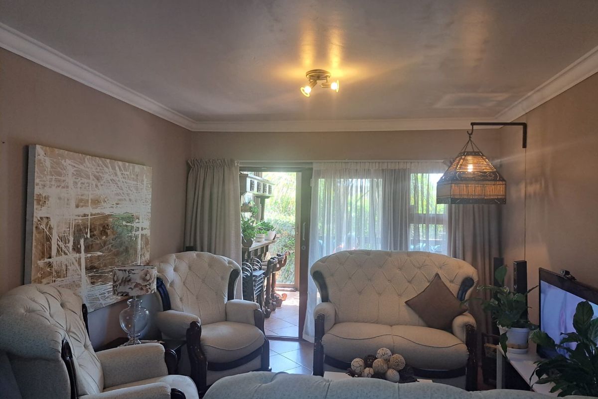 A comfortable living room featuring tiled flooring, cove molding, and a sliding glass door providing access to an outdoor patio area.
