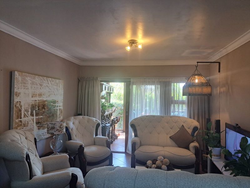 A comfortable living room featuring tiled flooring, cove molding, and a sliding glass door providing access to an outdoor patio area.