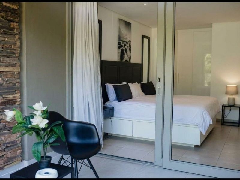 Modern bedroom featuring tiled floors, built-in cupboards, and recessed lighting, with direct access to an outdoor patio through large sliding glass doors.