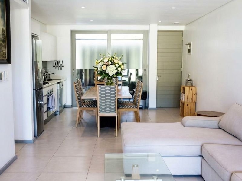 Modern open-plan living area featuring a sleek kitchen with built-in appliances, tiled flooring, and seamless access to the outdoor patio through sliding glass doors.
