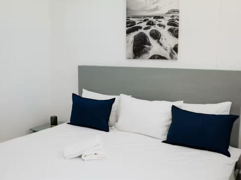 A well-maintained bedroom featuring a neutral grey built-in headboard, providing a clean and comfortable sleeping space.