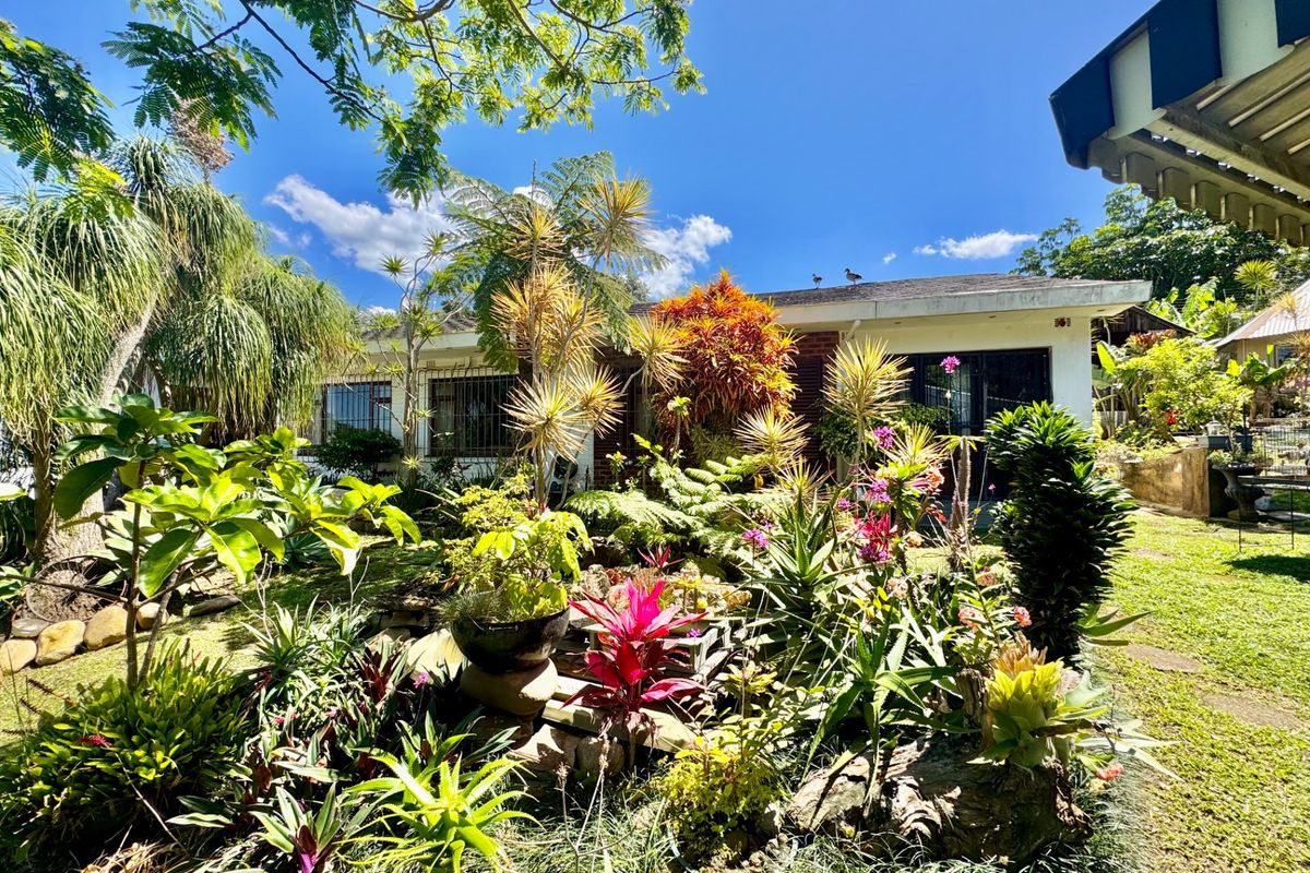 A view of the rear garden and backyard area featuring established landscaping and access to the home via sliding glass doors.