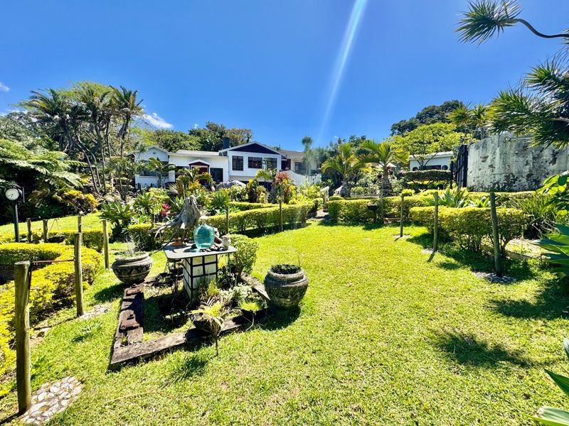 A well-maintained garden area featuring established hedging and landscaping, providing a pleasant outdoor space with views toward the main residence.