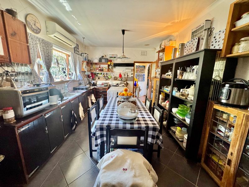 A functional kitchen featuring built-in cabinetry, tiled flooring, and a split-system air conditioner, offering a practical layout for daily meal preparation.