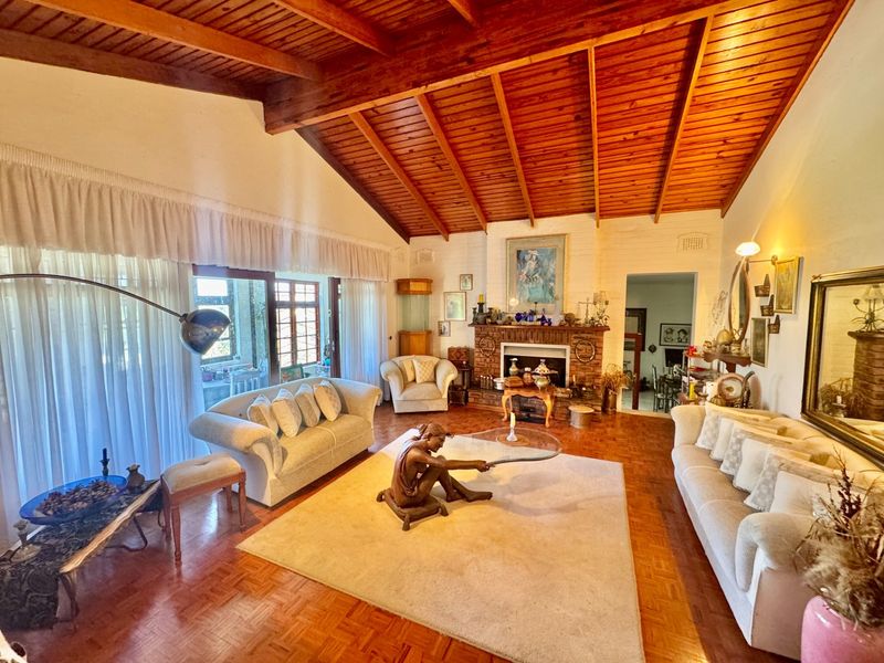 Spacious living room featuring a vaulted timber ceiling, classic brick fireplace, and parquet flooring, with large sliding doors providing access to the patio.