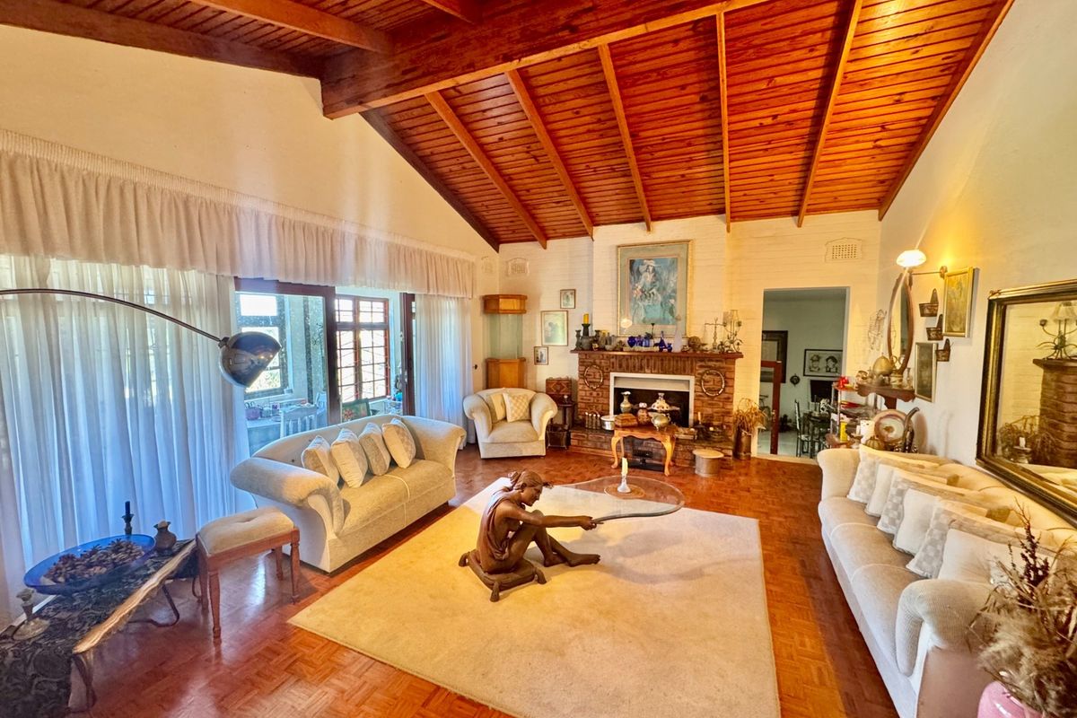 Spacious living room featuring a vaulted timber ceiling, classic brick fireplace, and parquet flooring, with large sliding doors providing access to the patio.