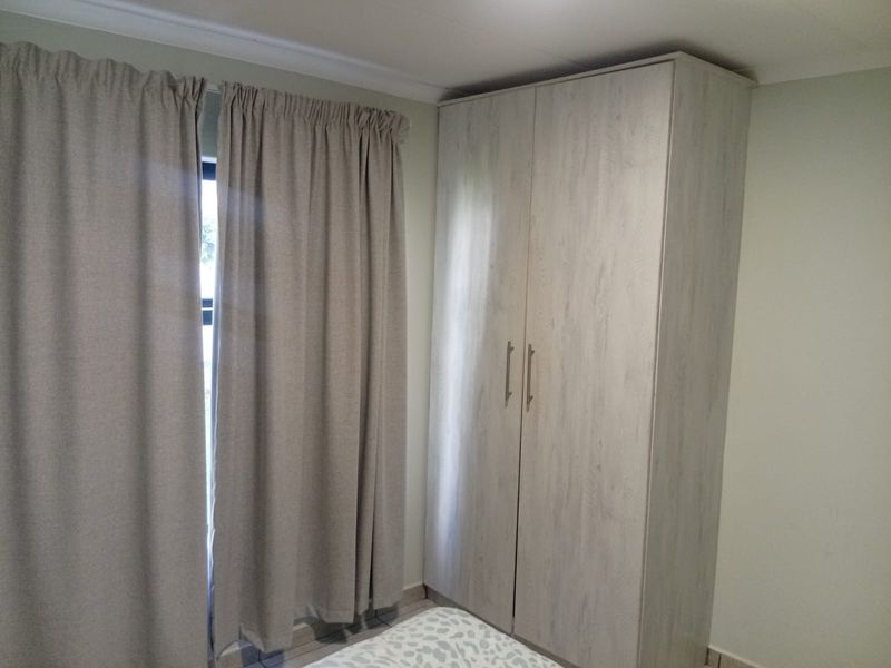 A bedroom featuring a light wood-finish built-in wardrobe and neutral wall tones.