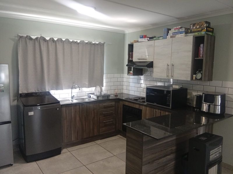 A functional kitchen featuring modern wood-look cabinetry, dark countertops, subway tile backsplash, and integrated appliances, providing a clean and practical cooking space.