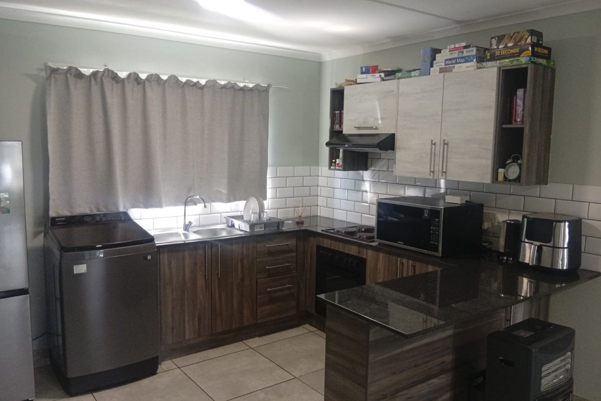 A functional kitchen featuring modern wood-look cabinetry, dark countertops, subway tile backsplash, and integrated appliances, providing a clean and practical cooking space.