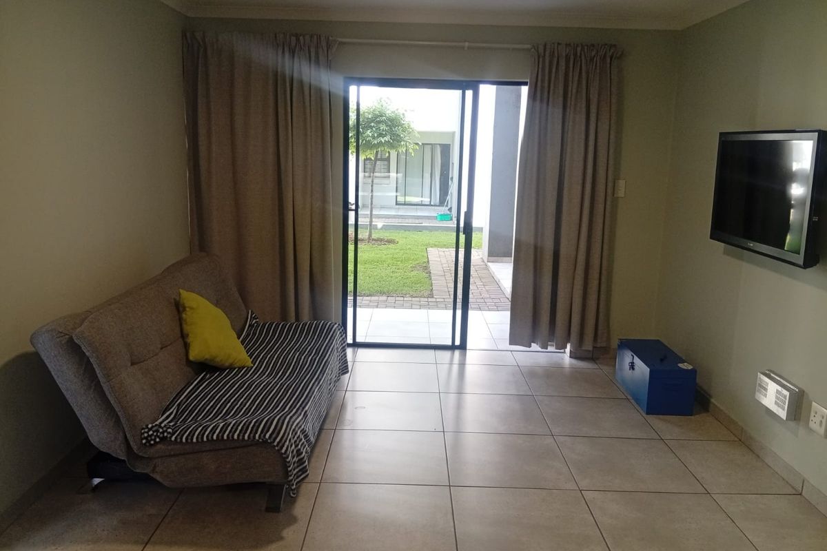 A living room featuring tiled flooring and a sliding glass door providing direct access to the outdoor garden area.