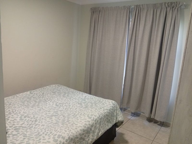 A functional bedroom featuring neutral wall tones and tiled flooring, providing a clean and simple space ready for personalization.