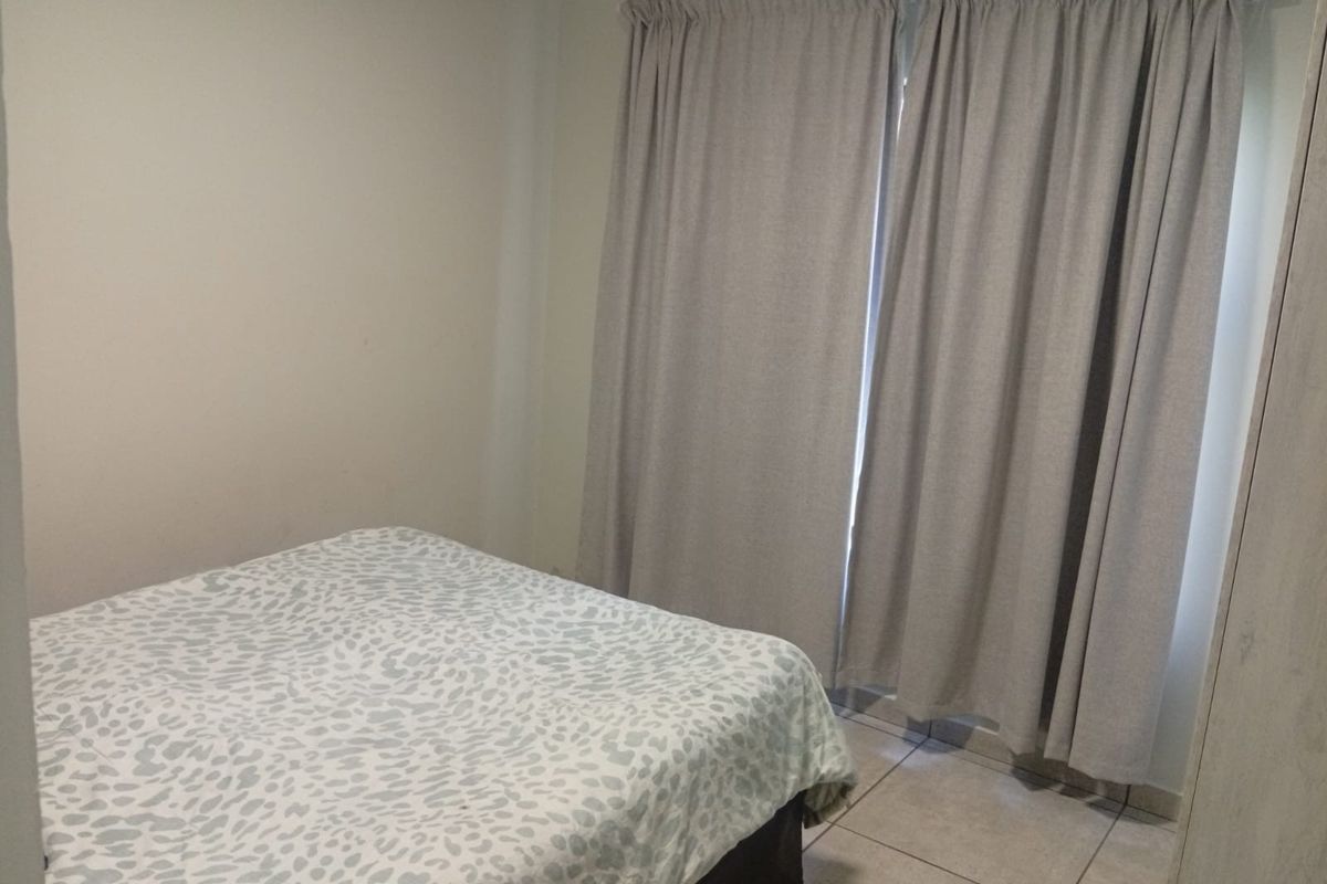 A functional bedroom featuring neutral wall tones and tiled flooring, providing a clean and simple space ready for personalization.