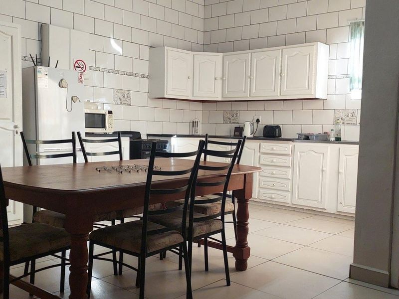 Open plan kitchen and dining area featuring white cabinetry, tiled splashbacks, and tiled flooring, providing a functional space for cooking and family meals.
