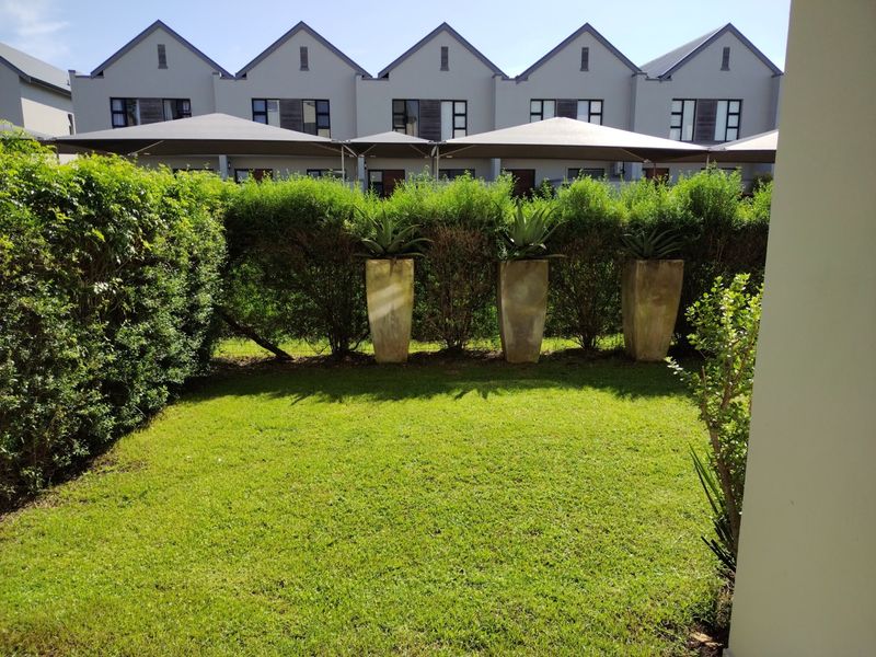 A well-maintained private rear garden featuring a manicured lawn and established hedging, providing a pleasant outdoor space for the apartment.