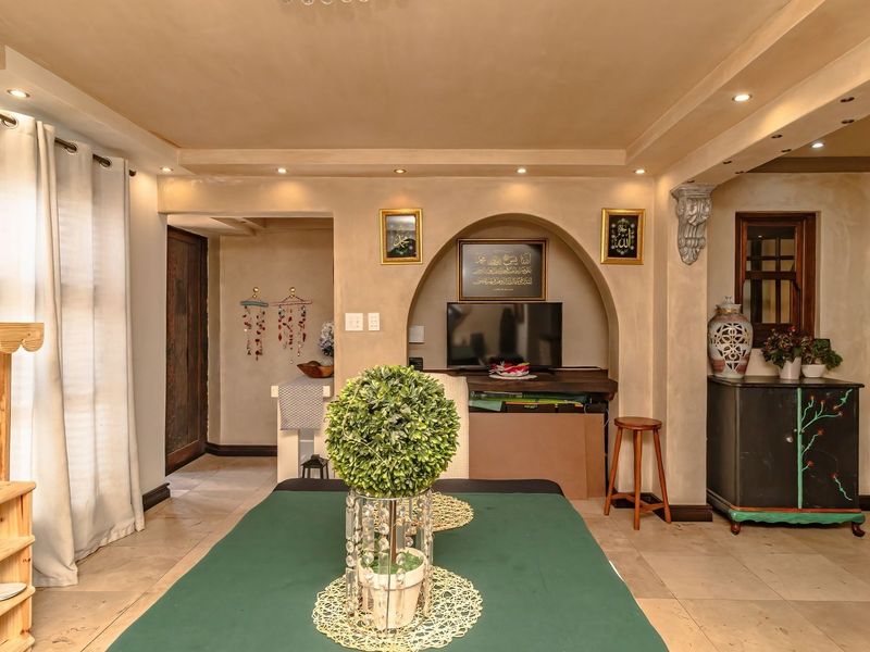 A living room featuring a distinctive arched wall niche, recessed ceiling lighting, and neutral tiled flooring, offering a warm and inviting atmosphere.