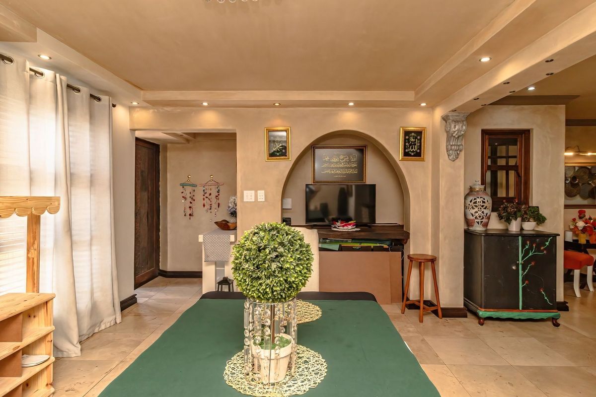 A living room featuring a distinctive arched wall niche, recessed ceiling lighting, and neutral tiled flooring, offering a warm and inviting atmosphere.