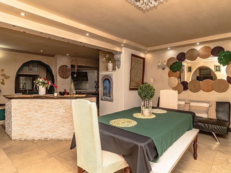 Open-plan living and dining area featuring tiled flooring, recessed ceiling lighting, and a stone-clad breakfast bar connecting to the kitchen space.