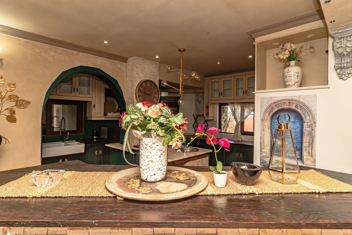 A characterful kitchen featuring custom cabinetry, a farmhouse sink, and unique architectural details including an arched entryway and decorative stone accents.
