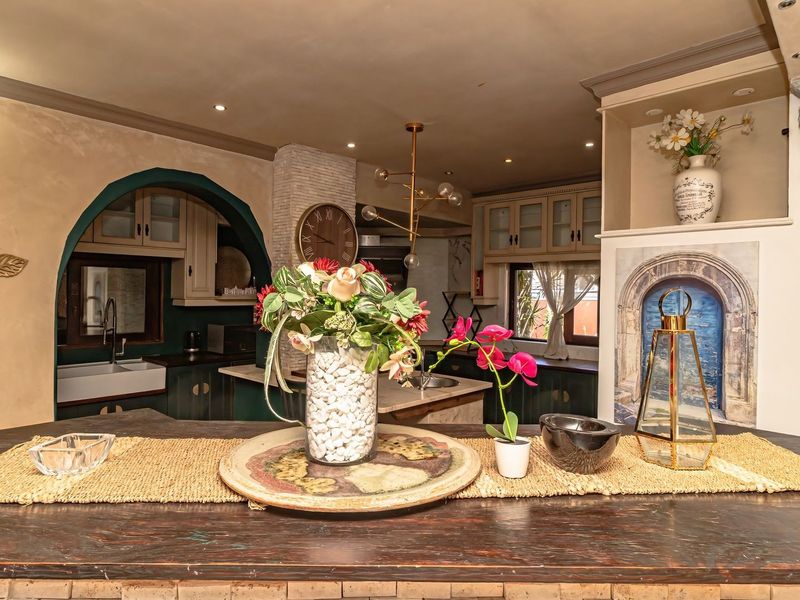 A characterful kitchen featuring custom cabinetry, a farmhouse sink, and unique architectural details including an arched entryway and decorative stone accents.