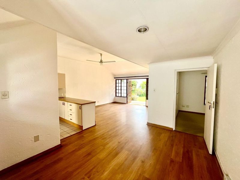 Spacious open-plan living area featuring laminate flooring, a ceiling fan, and a functional kitchen layout with direct access to the outdoor patio.