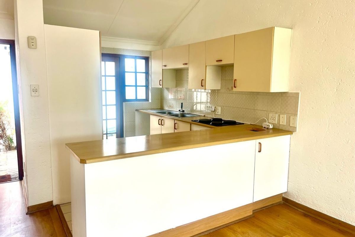 A functional kitchen featuring built-in cabinetry, a breakfast bar, and a tiled backsplash, offering a clean and practical layout for a retirement village unit.