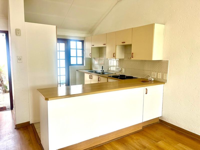 A functional kitchen featuring built-in cabinetry, a breakfast bar, and a tiled backsplash, offering a clean and practical layout for a retirement village unit.