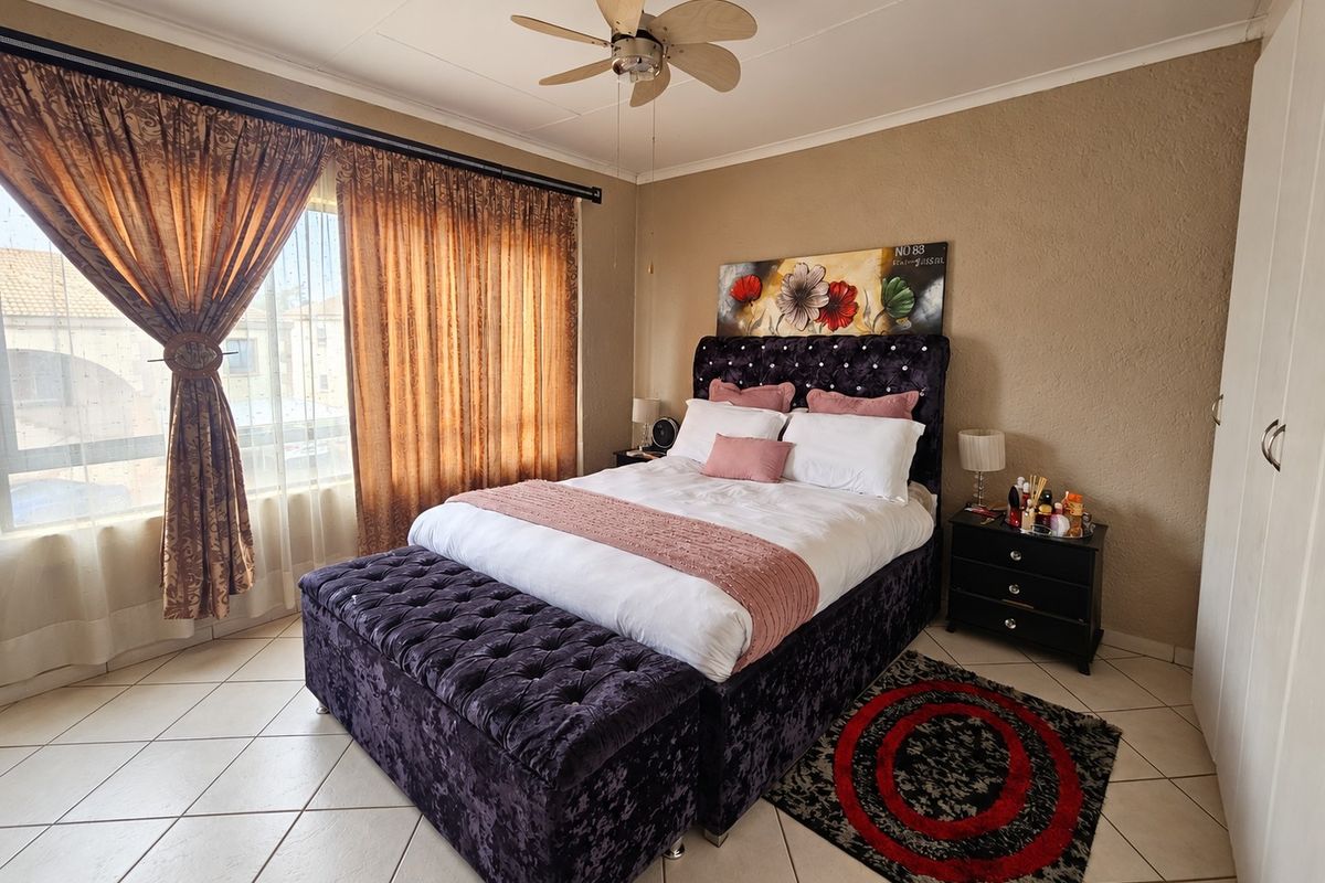 A bedroom featuring tiled flooring, a ceiling fan, and built-in wardrobe storage.