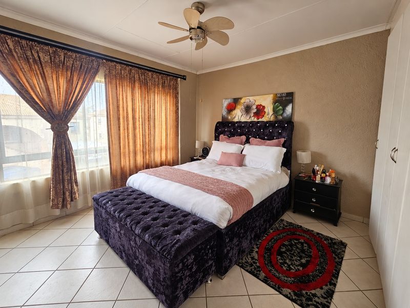 A bedroom featuring tiled flooring, a ceiling fan, and built-in wardrobe storage.