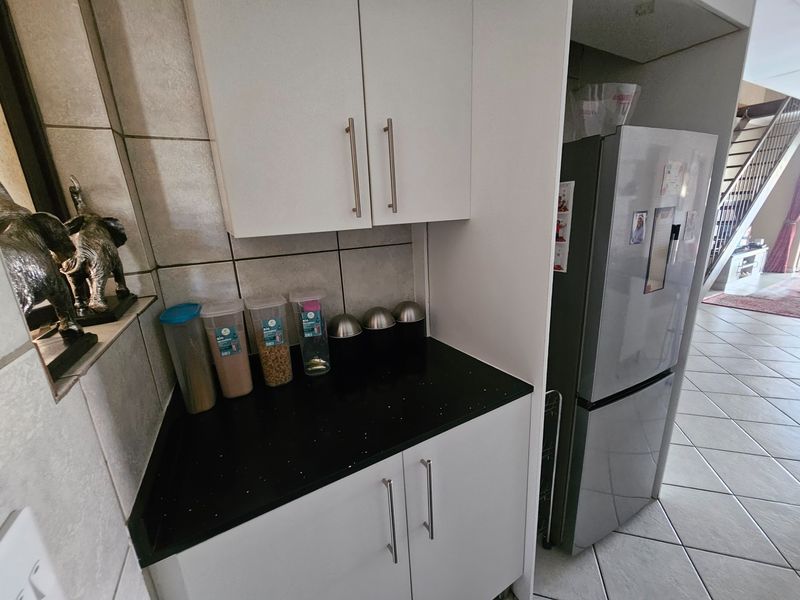A compact kitchen area featuring white cabinetry, a dark stone countertop, and tiled backsplash, providing functional storage and preparation space.